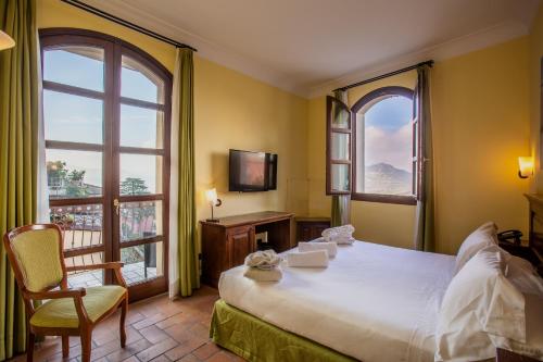 a bedroom with a large bed and two windows at Oste del Castello Wellness & Bike Hotel in Verucchio