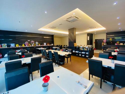 un restaurant avec des tables et des chaises blanches et un buffet dans l'établissement Just Hotel BP, à Batu Pahat