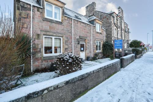 a brick building with snow on the ground next to a street at mySTAYINN Strathblane House in Inverness