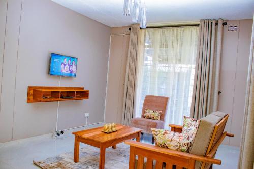 sala de estar con TV, mesa y silla en R Executive Apartments en Harare