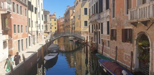 un canal entre dos edificios con un puente y barcos en Magic Casanova Flat in the heart of Venice, en Venecia