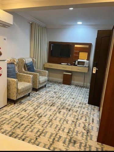 sala de estar con 2 sillas y TV en فندق أباهى3, en Al Hofuf
