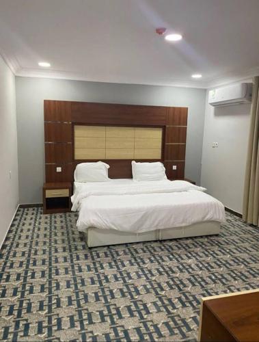 1 dormitorio con 1 cama grande y cabecero de madera en فندق أباهى3, en Al Hofuf