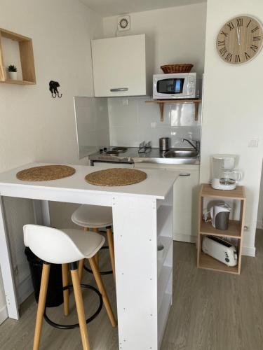 - une petite cuisine avec un comptoir blanc et des tabourets dans l'établissement Studio cabine, à Bolquère-Pyrénées 2000