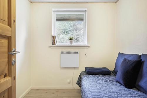 Un dormitorio con una cama con almohadas azules y una ventana en Sommerhus ved Vesterhavet, en Ulfborg