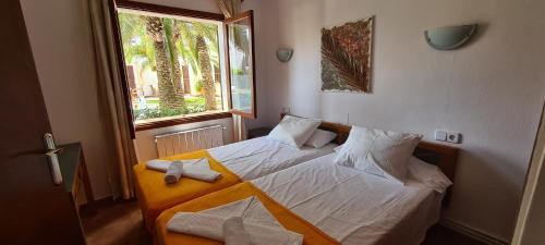 Schlafzimmer mit einem Bett mit weißer Bettwäsche und einem Fenster in der Unterkunft Apartamentos Osa Menor in Cala d´Or