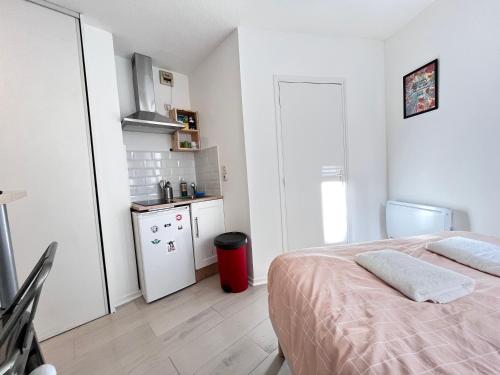 1 dormitorio blanco con 1 cama y cocina en Le Tressous - Studio sur place de Jaude Prefecture, en Clermont-Ferrand