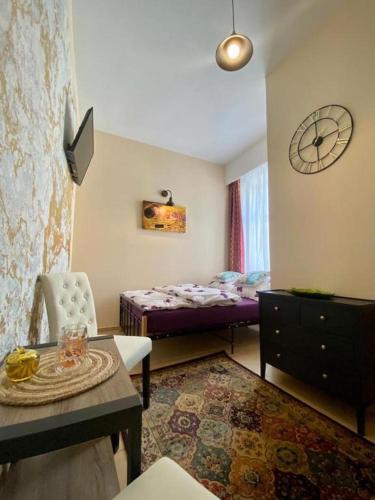 1 dormitorio con cama, mesa y reloj en Butikowe Pokoje Zdrój Głuchołazy, en Głuchołazy