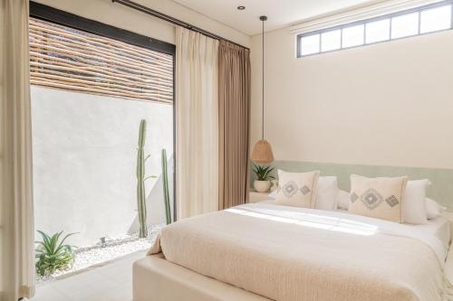 a bedroom with a large bed and a large window at YUCCA villas in Canggu