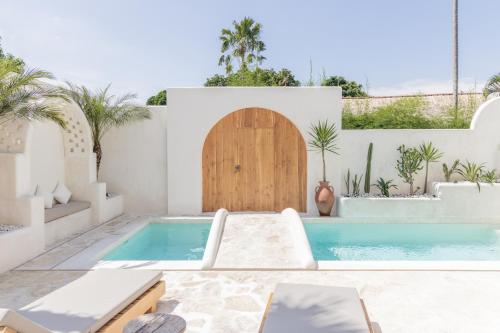 a house with a swimming pool and a wooden door at YUCCA villas in Canggu