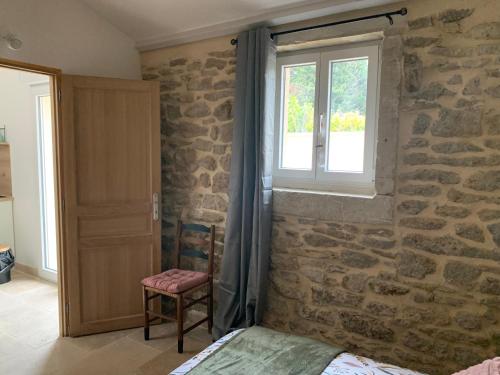 a bedroom with a stone wall and a window at LA MAGNANERIE in Grillon