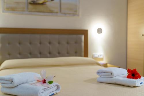 a hotel room with towels and flowers on a bed at Levantino Studios & Apartments in Vasilikos