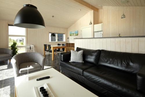 sala de estar con sofá de cuero negro y mesa en Lalandia Billund, en Billund