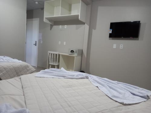 a bedroom with a bed and a desk and a tv at Sognare Hotel in Caçador