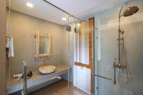 a bathroom with a sink and a glass shower at Three Monkeys Villas in Patong Beach