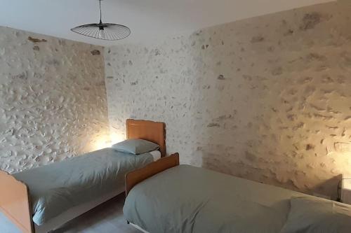 two beds in a bedroom with two lamps and a wall at Le Gîte de la fontaine in Neuvy-le-Roi