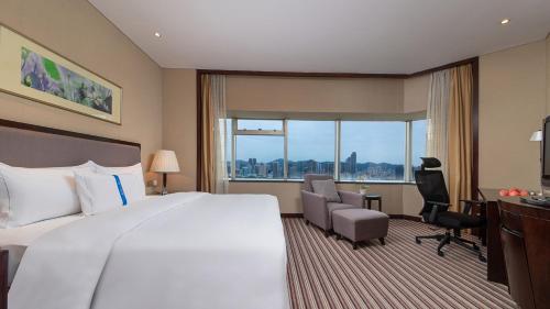 a hotel room with a large bed and a desk at Binbei Yiho Hotel in Xiamen