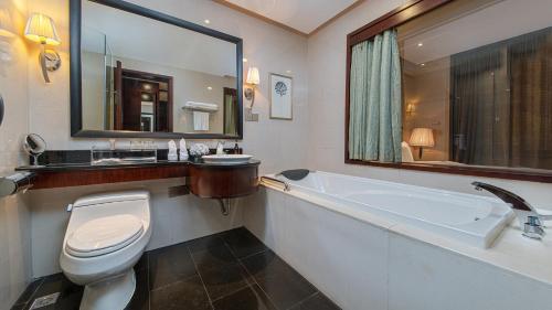 a bathroom with a toilet and a sink and a tub at Binbei Yiho Hotel in Xiamen