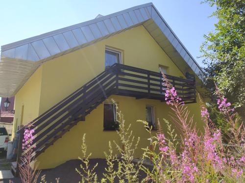 a yellow house with a staircase on the side of it at Apartmány u Torína in Boží Dar
