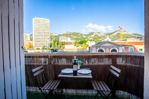 - une table avec une bouteille de vin et 2 chaises sur un balcon dans l'établissement La Clé T2 Love Room Balnéo, Clim, Proche Gare, à Toulon