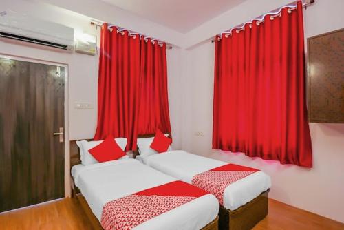 two beds in a room with red curtains at HZ INN in Hyderabad