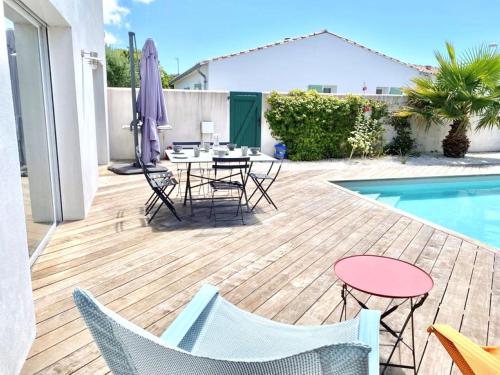 um pátio com cadeiras, uma mesa e uma piscina em Villa piscine a La Flotte en Re em La Flotte