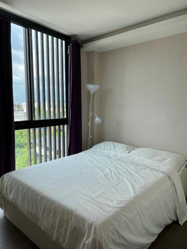 a bedroom with a white bed and a large window at The Remarkable ศูนย์วิจัย2 in Bangkok