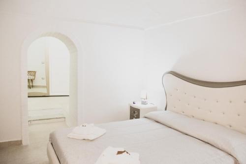 a white bedroom with a bed with two towels on it at Acasadifelice in Matera