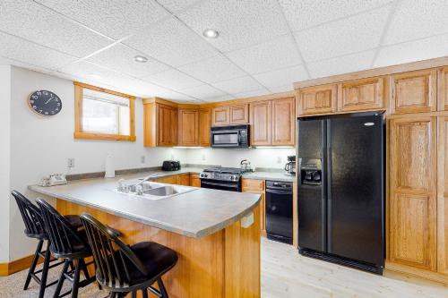 a kitchen with wooden cabinets and a black refrigerator at Jay Peak Village Home 367B in Jay