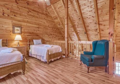 een slaapkamer in een blokhut met 2 bedden en een blauwe stoel bij Evening Shade #129 in Sevierville