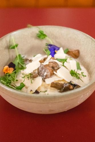 a bowl of soup with cheese and greens in it at Le Val Thorens, a Beaumier hotel in Val Thorens