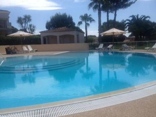 une grande piscine bleue avec des chaises et des parasols dans l'établissement Villa Royal Mougins Golf Club, à Mougins