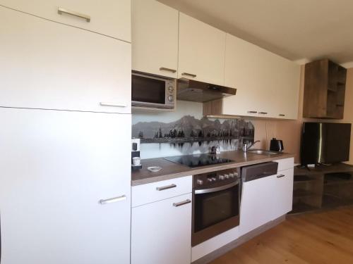 a white kitchen with a stove and a microwave at Ferienwohnung Konrad in Kirchdorf in Tirol