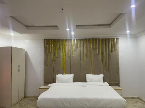 um quarto com uma cama grande e lençóis brancos em White Gold Hotel em Ikeja