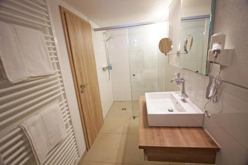 a white bathroom with a sink and a shower at Hotel Adler in Bad Friedrichshall