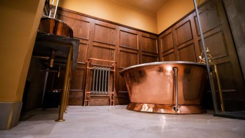 a copper bath tub in a room with wooden walls at The Funky Monk in Durham