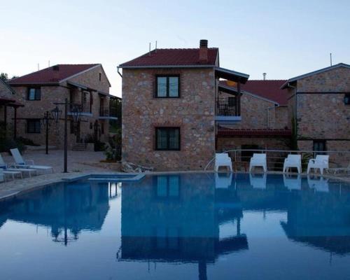 a swimming pool with white chairs in front of a building at Lithea Mountain Resort in Florina