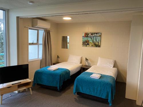 a hotel room with two beds and a television at City Towers Apartments in Auckland