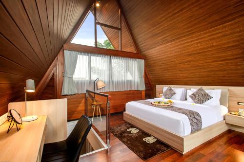a bedroom with a bed and a desk and a window at Kanhara Villas Ubud by Pramana Villas in Ubud