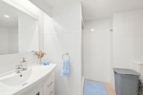 a white bathroom with a sink and a shower at The Commodore in Nelson Bay