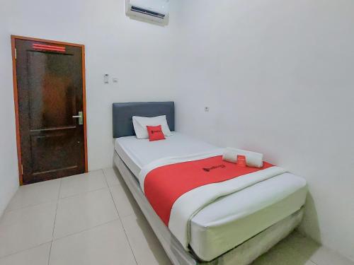 ein kleines Schlafzimmer mit einem Bett mit einer roten Decke in der Unterkunft Reddoorz at Cempaka Guesthouse Tarakan in Sibengkok