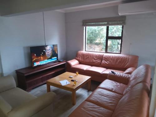 a living room with a leather couch and a tv at Bergview Chalet, Cathkin in Bergview