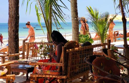 a group of people sitting on a bench on the beach at Sipano Beach Lodge Kiwengwa in Kiwengwa