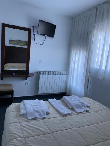 a bedroom with a bed with two towels and a mirror at Hostal La Pinilla in Segovia