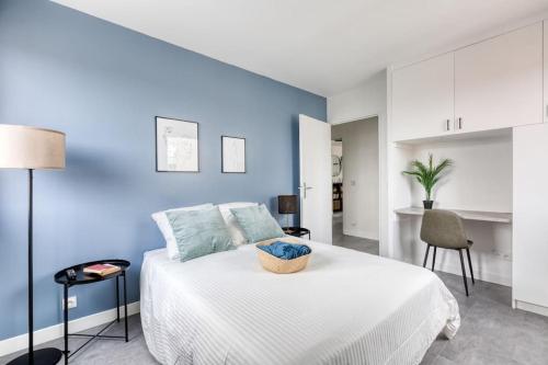 sypialnia z białym łóżkiem i niebieską ścianą w obiekcie Premium Flat 6 People with billard and Terrace Stade de France w mieście Saint-Denis