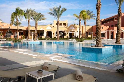 een groot zwembad met palmbomen en gebouwen bij Jaz Dar El Madina in Baai van Coraya