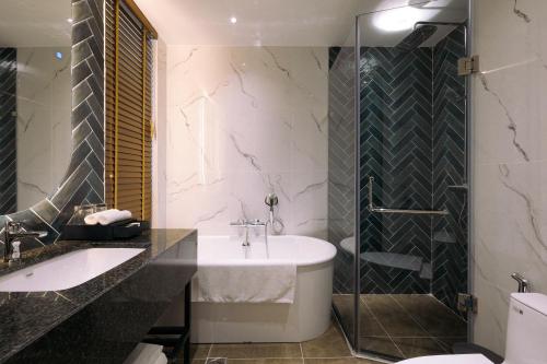 a bathroom with a tub and a sink and a shower at La Vela Hue Hotel in Hue