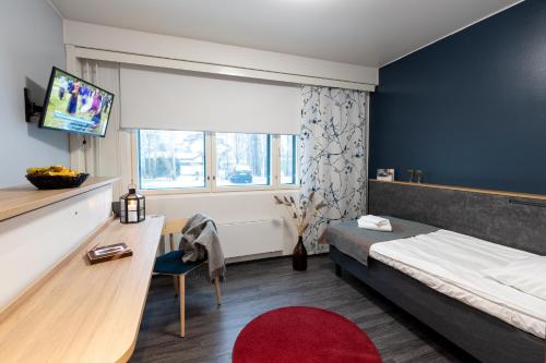 Dormitorio con cama, escritorio y TV en Hotel Linnasmäki, en Turku