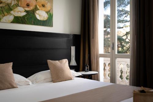 una camera con un letto bianco e una finestra di Hotel Helvetia Thermal Spa a Porretta Terme