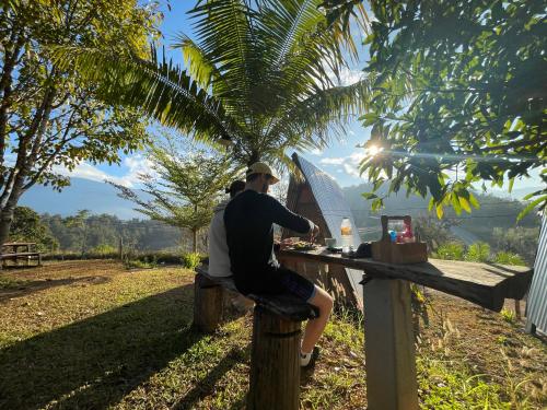 two people sitting at a bar on a fence at Monsonkeang Camping view ม่อนสันเกี๋ยง in Mae Chaem